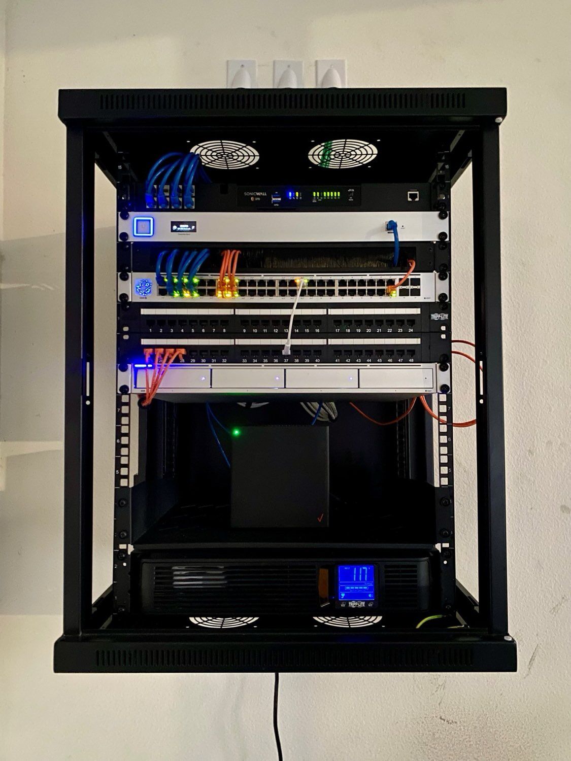 Clean, professionally cabled low-voltage network rack with SonicWall firewall, managed switches, and structured patch panels