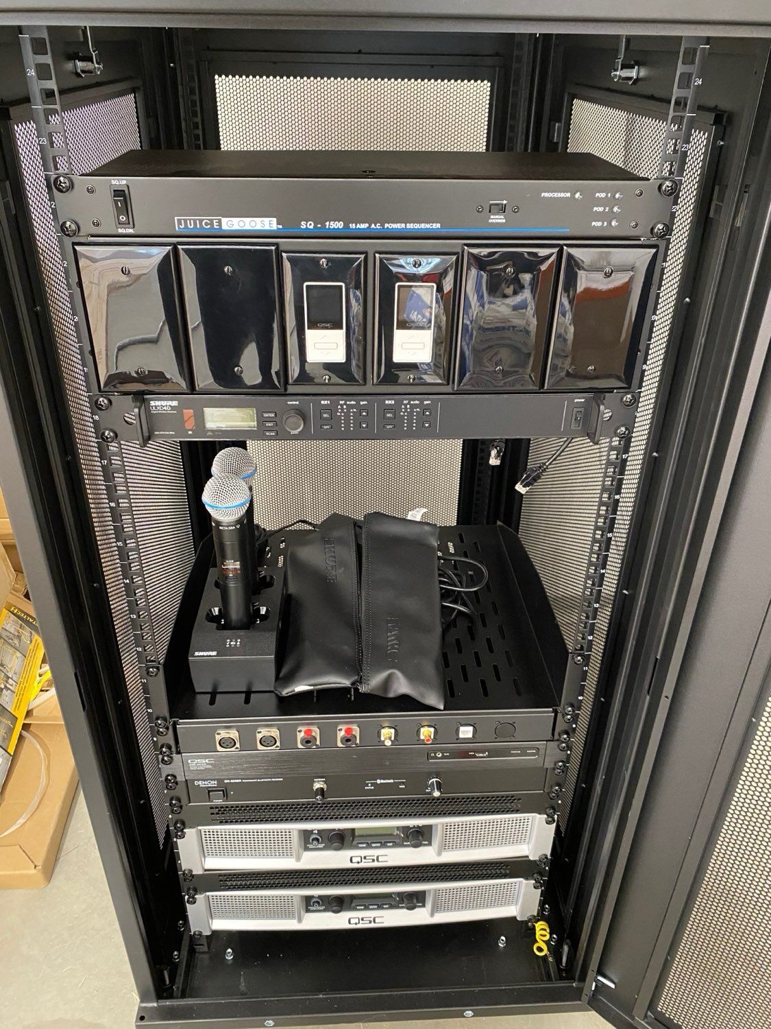 Professionally built AV equipment rack featuring QSC amplifiers, a Shure ULXD wireless system, Denon audio processor, and Juice Goose power sequencing