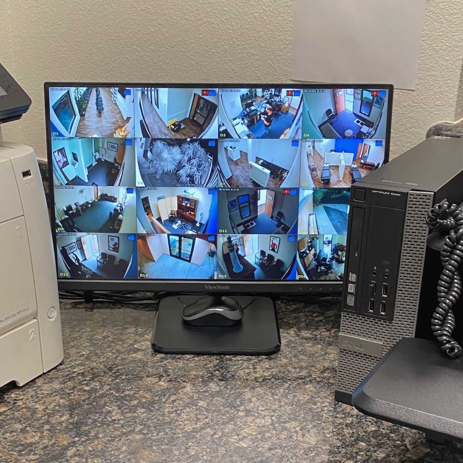 Commercial security monitoring station showing a 16-camera surveillance grid covering offices and hallways